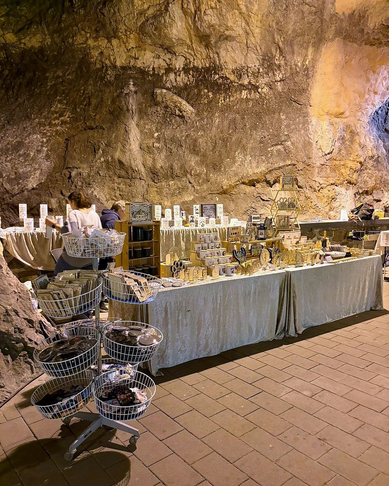 Stand mit Holzarbeiten und Geschenkartikeln vor der Felswand der Höhle