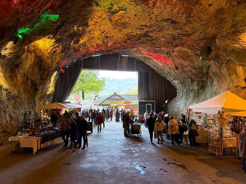 Blick aus der Höhle zum Eingang: Besucher zwischen den Marktständen unter dem farbig beleuchteten Gewölbe