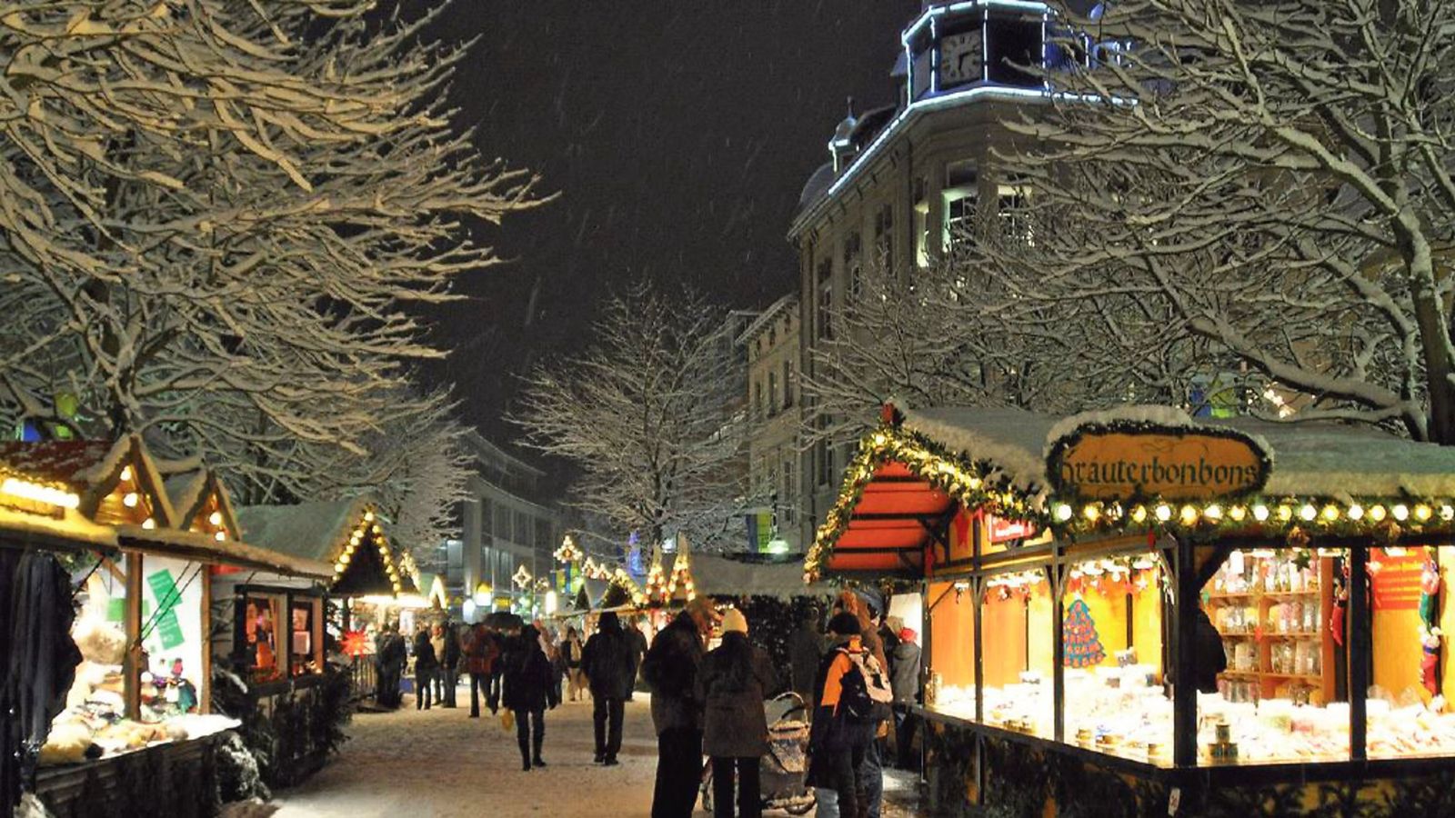 Weihnachtsmarkt in Brühl zur blauen Stunde, beleuchtete Buden und verschneite Bäume